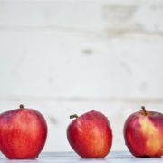 Row of five red apples with a grey background