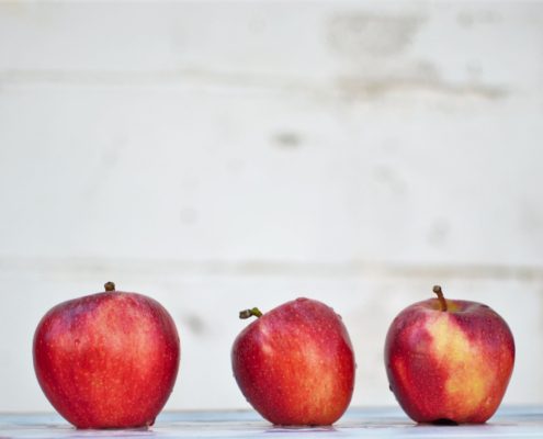 Row of five red apples with a grey background