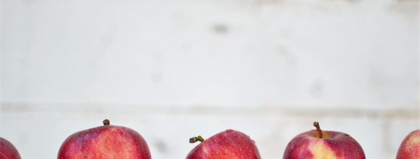 Row of five red apples with a grey background